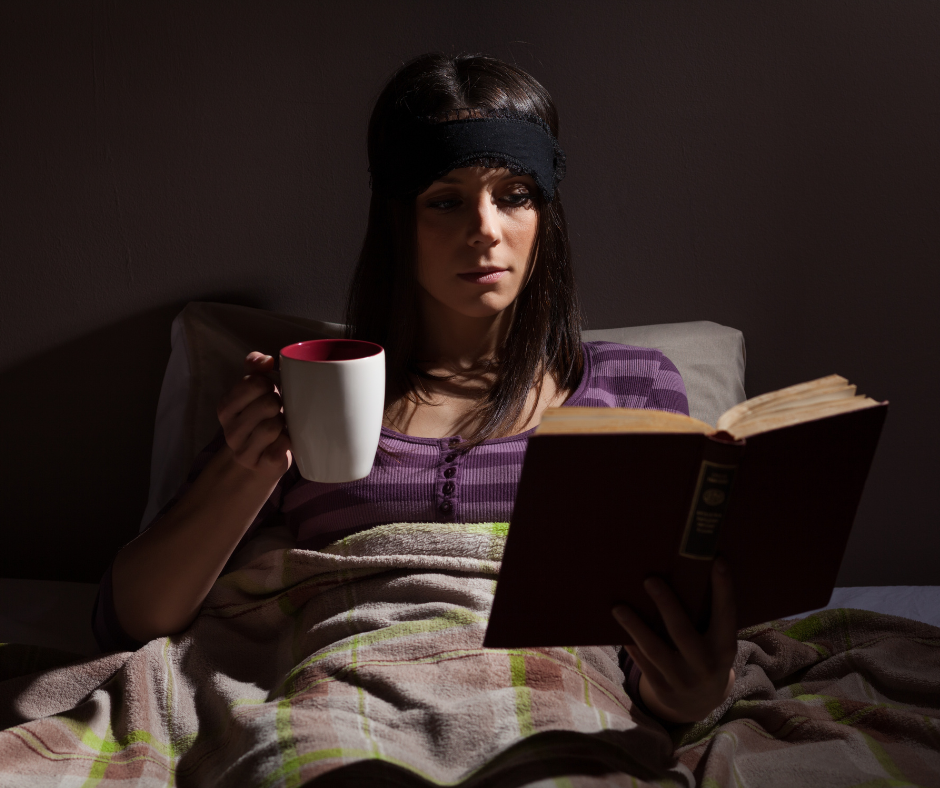 Femme détendue dans son lit, lisant un livre et dégustant une tisane pour favoriser le sommeil.
